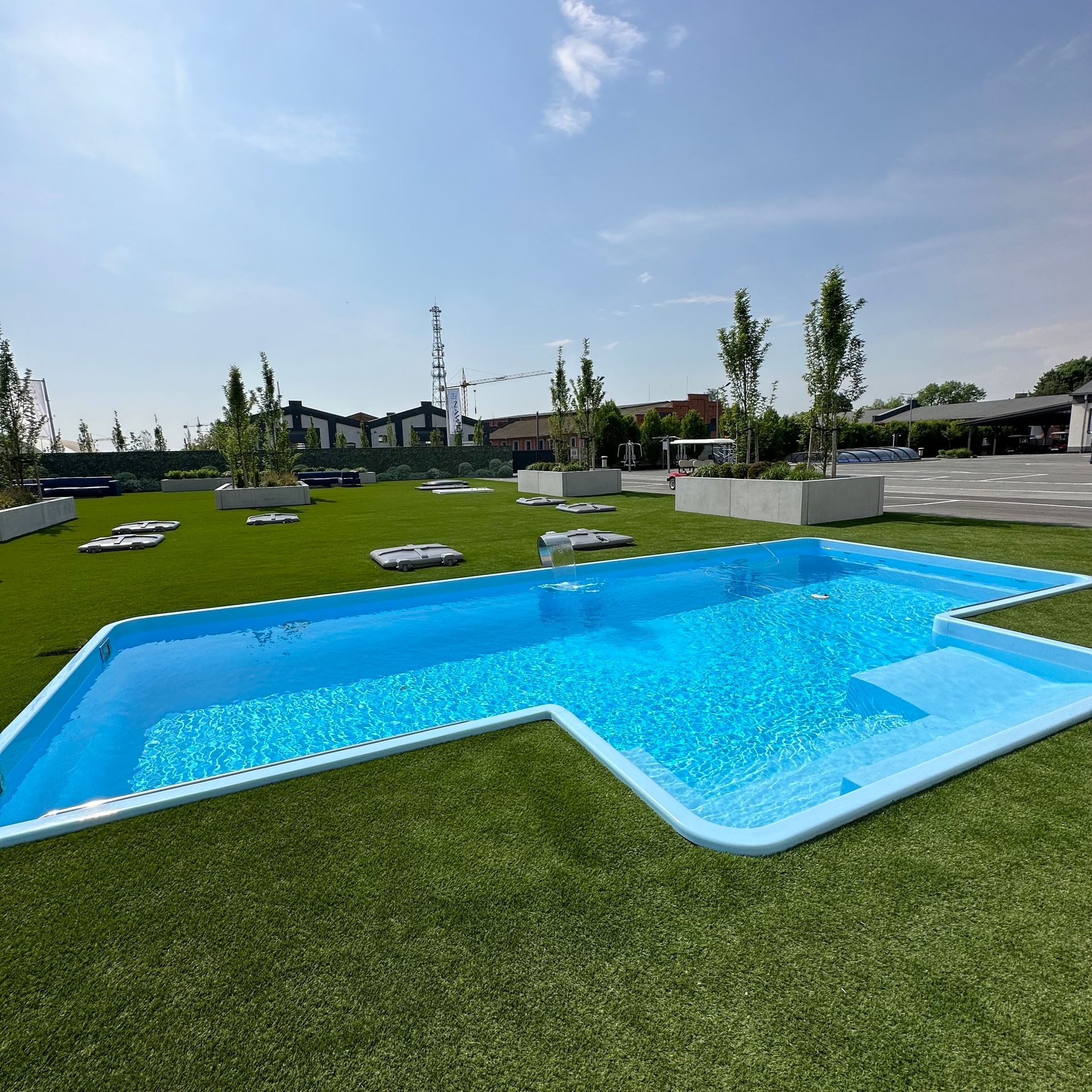 Luxuriöser Exclusive-Pool mit Carbon/Aramid-Schicht auf Kunstrasenfläche vor Showroom – maximale Haltbarkeit und Eleganz