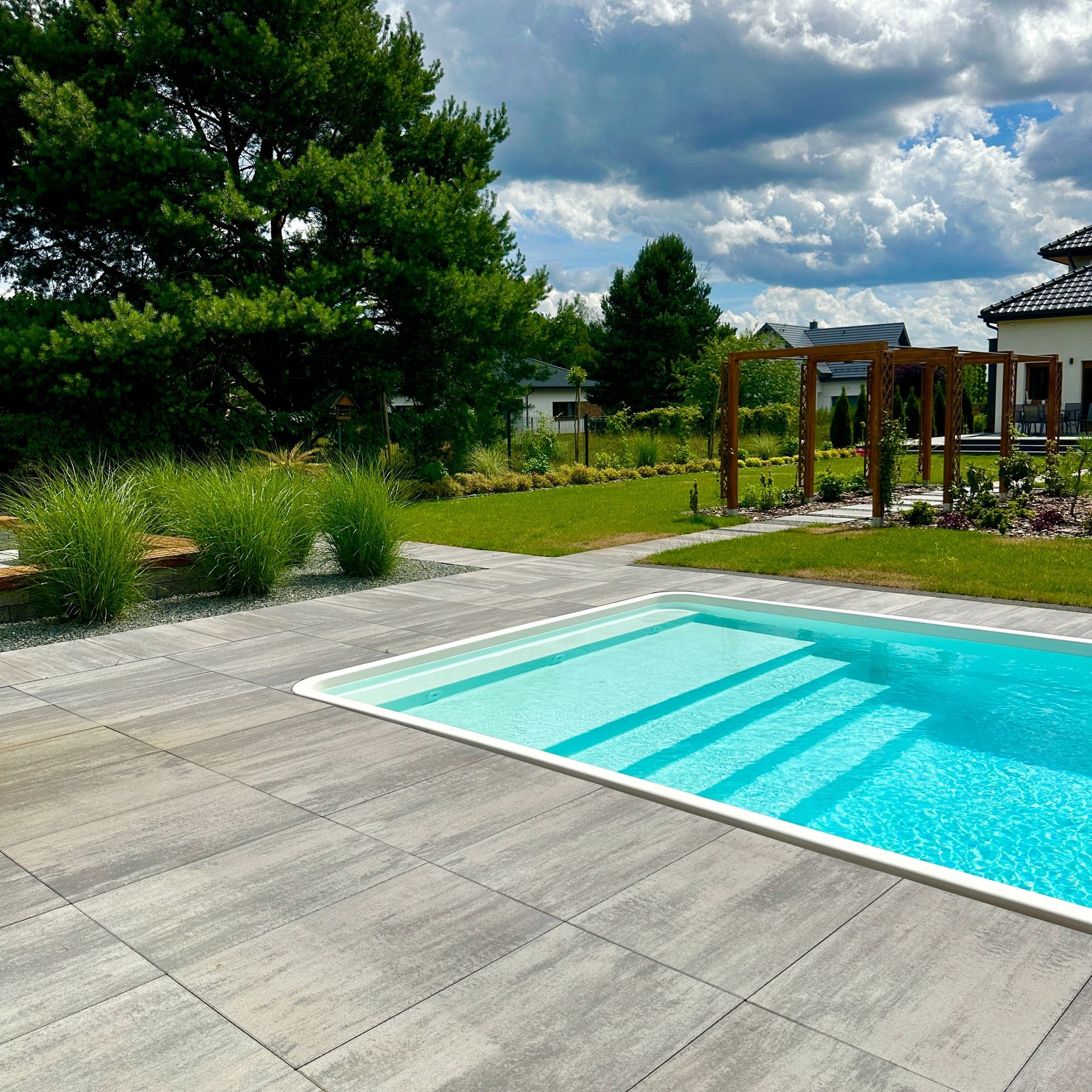 Design-Pool StarPool mit Carbon/Aramid-Verstärkung, eingebettet in eine moderne Gartengestaltung mit grauen Fliesen und Begrünung