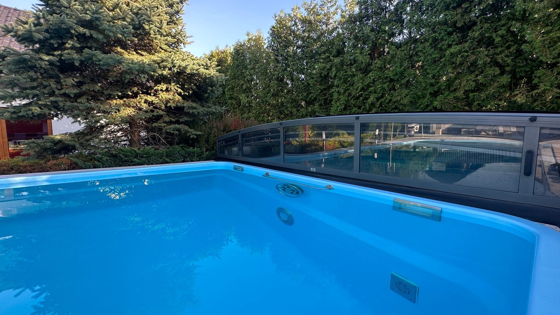 Sauberer Gartenpool mit klarem Wasser, Poolreiniger im Einsatz und Sonnenschein – Symbol für effektive Poolpflege im Sommer.