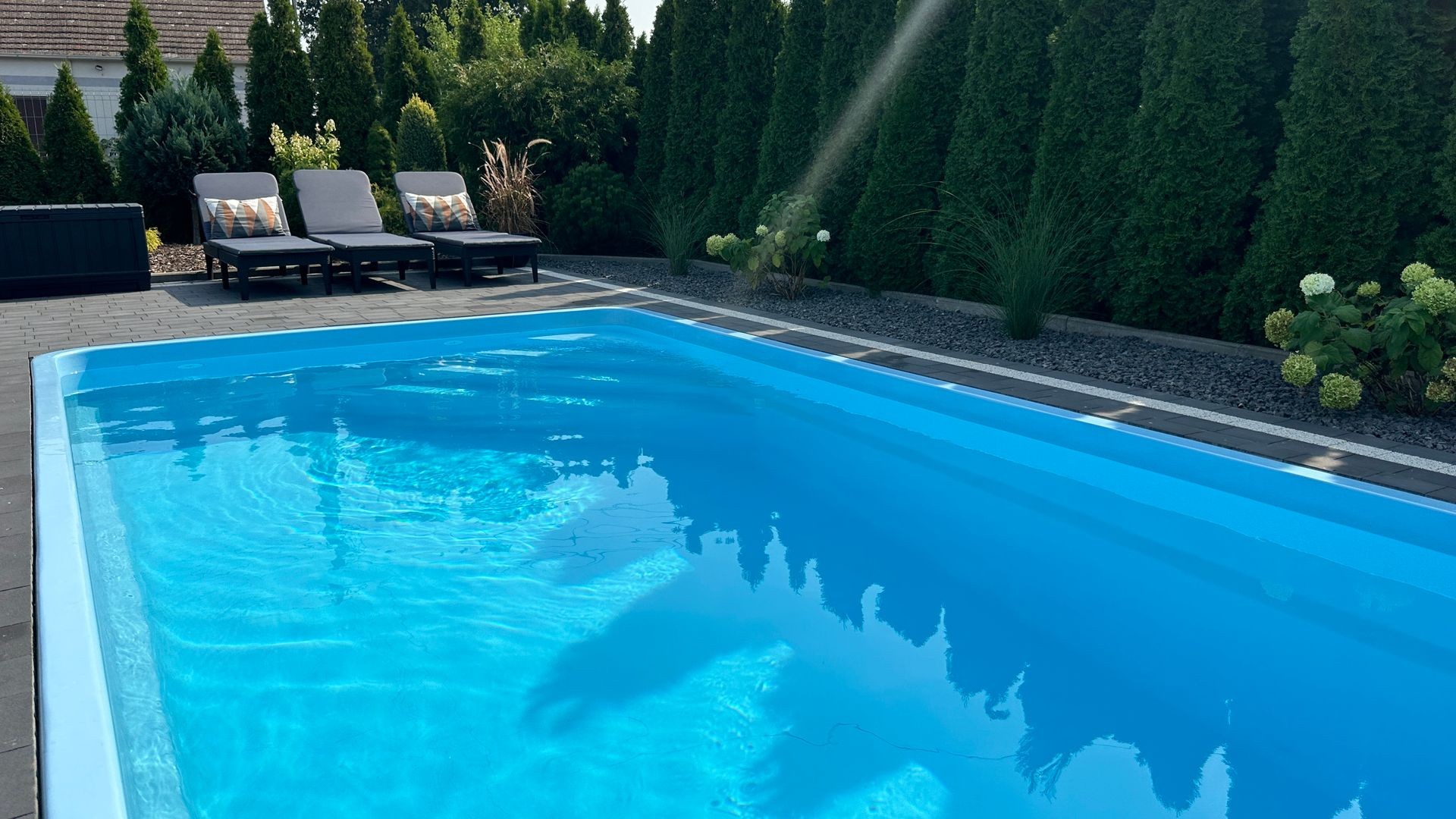 Moderner Gartenpool aus GFK, harmonisch in die Terrassenlandschaft integriert – ein Beispielprojekt von PoolsFactory